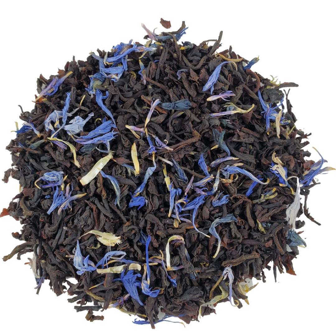 Dry black tea leaves with blue and yellow flowers on a white background