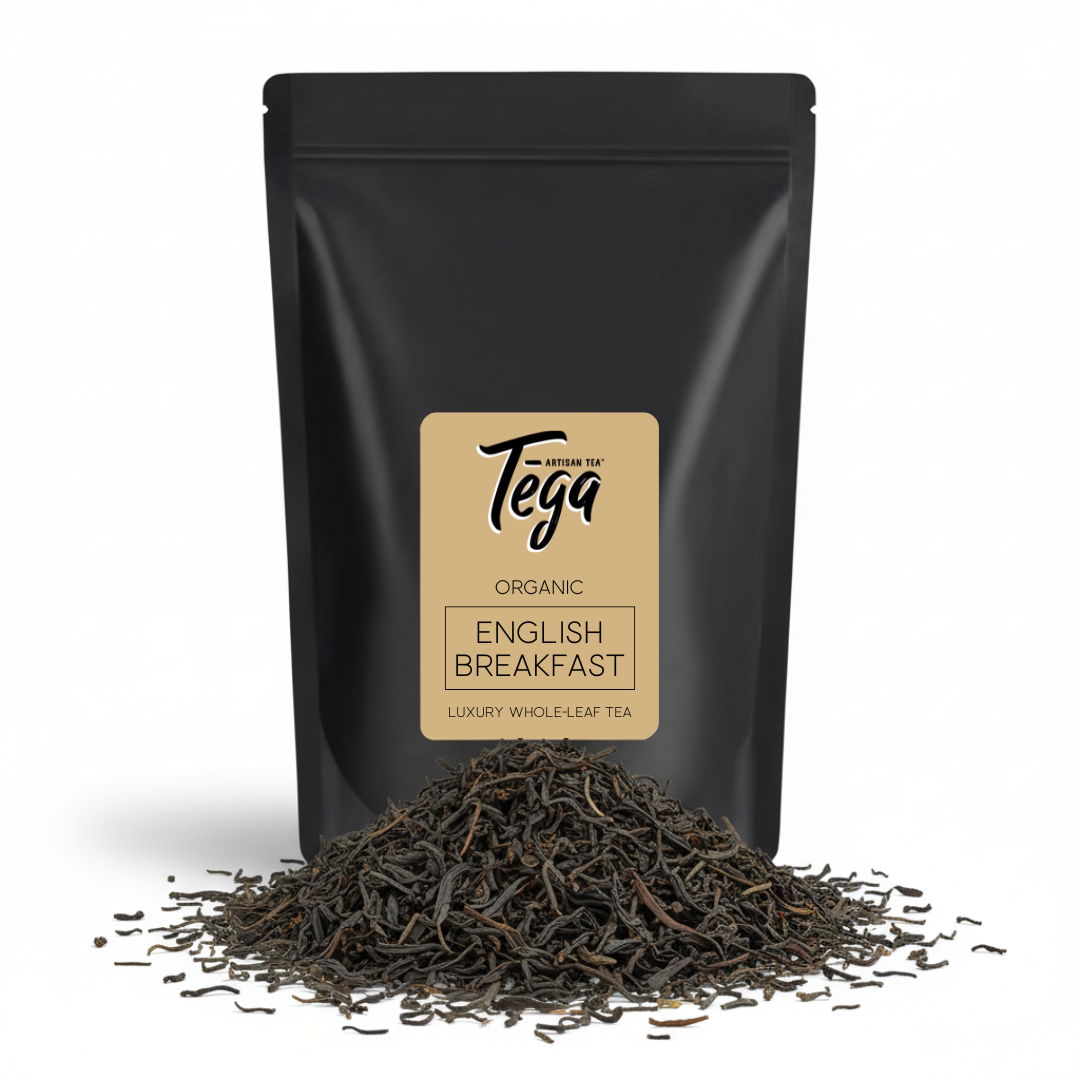 Black tea packaging with Tega label and loose tea leaves on a white background