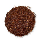 Round pile of brown rooibos tea leaves on a white background