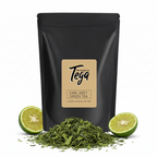Black tea packaging with 'Tega' brand label, green tea leaves, and limes on a white background