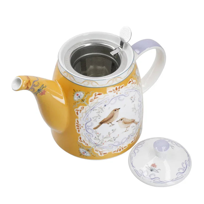 Yellow teapot with bird design on a white background