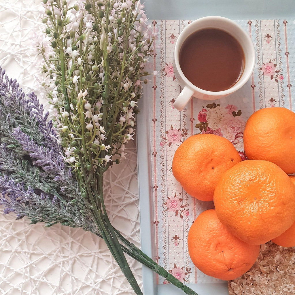 Oranges, a cup of tea, and flowers on a textured surface with floral pattern