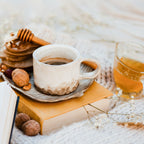 Ceramic mug with coffee, glass of honey water, and snacks on a textured surface