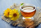 Glass of amber liquid with yellow flowers on a textured surface