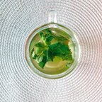 Glass of green tea with mint leaves on a textured white surface