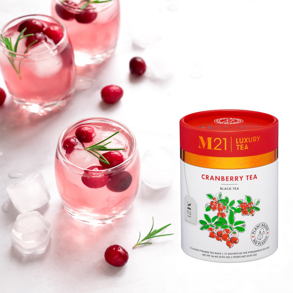 Cranberry tea with glasses of cranberry juice and M21 Cranberry Tea packaging on a white background