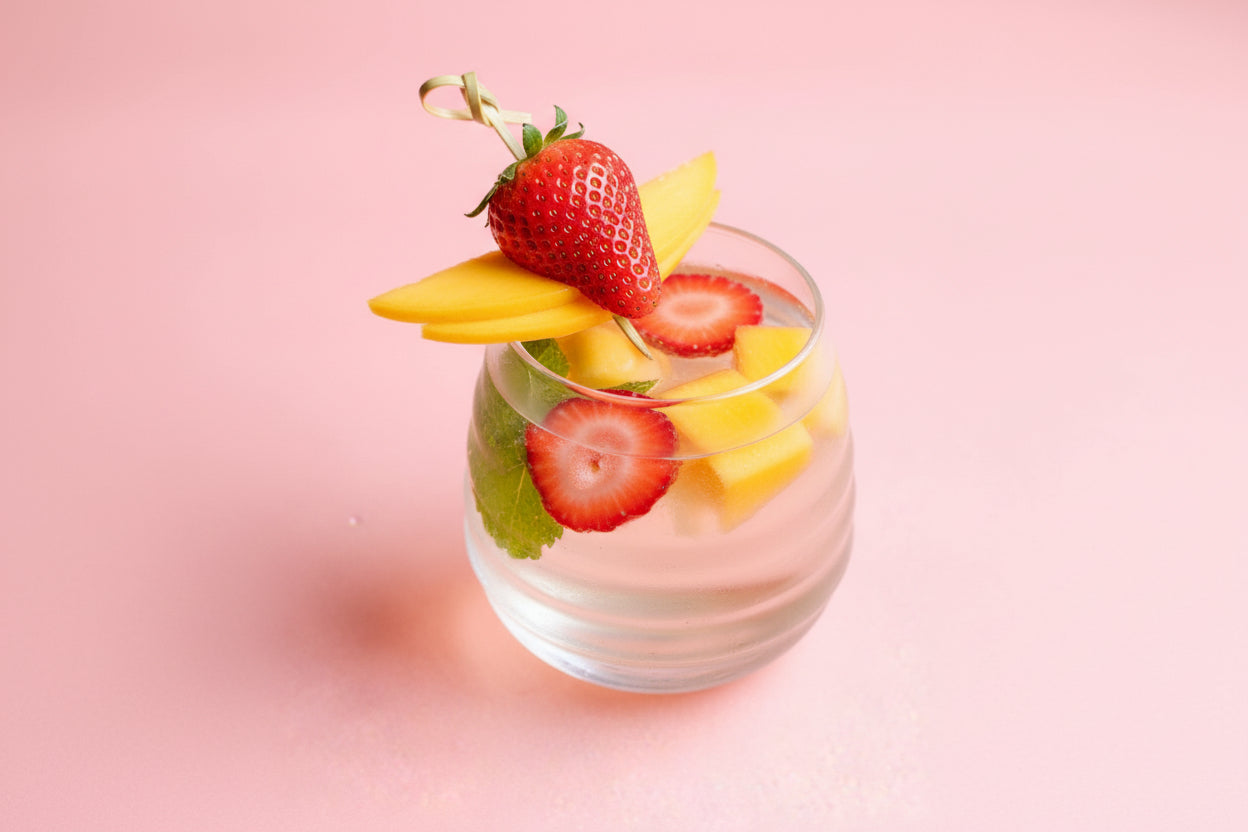 Glass of dessert with fruit on a pink background